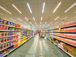 A person’s hands holding a packaged food item, closely examining the nutrition facts label in a grocery aisle.