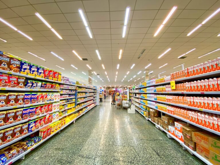 A person’s hands holding a packaged food item, closely examining the nutrition facts label in a grocery aisle.