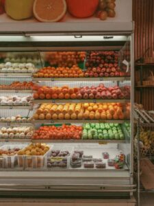 A shopper compares food labels beside fresh produce and clearly separated packaged groceries.