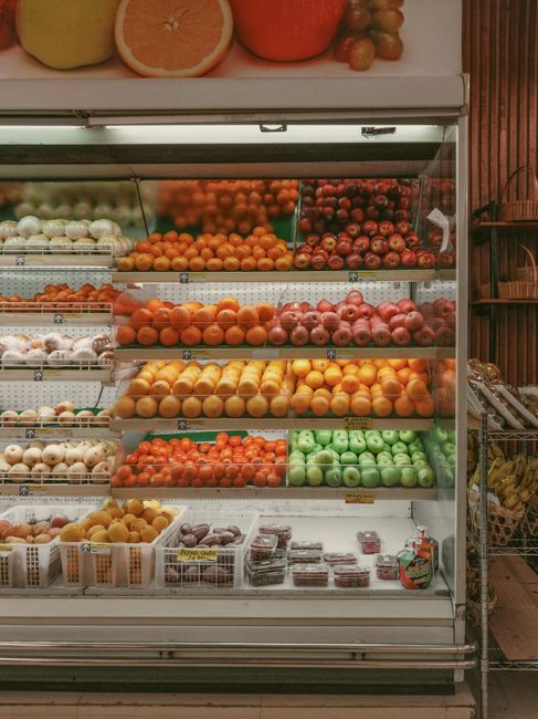 A shopper compares food labels beside fresh produce and clearly separated packaged groceries.